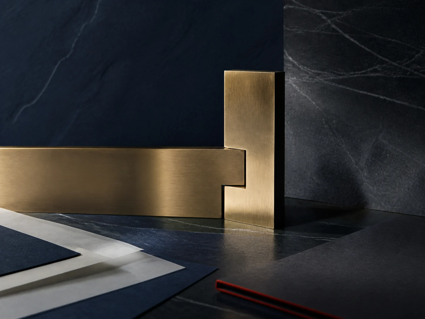 Precision brass forms aligned over layered transaction papers on a dark stone surface
